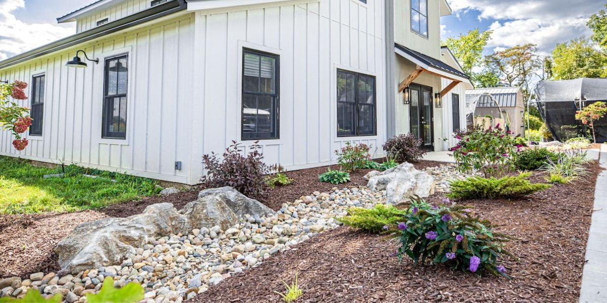 front of house with landscaping that includes large boulders, river rocks, flowers and plants