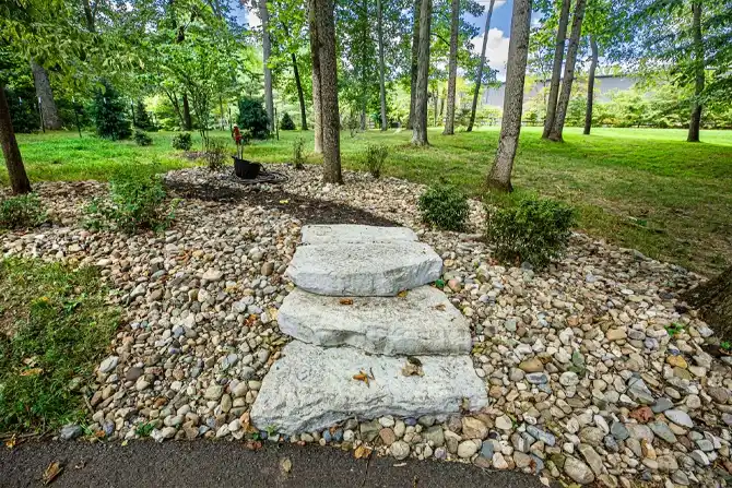 Rock and mulch landscape bed with plants, a water fountain, and large boulders as the perimeter