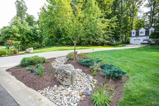 Front view of landscaping done with mulch, plants, a gravel walkway