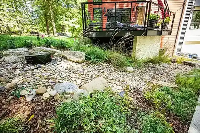 Rock and mulch landscape bed with plants, a water fountain, and large boulders as the perimeter