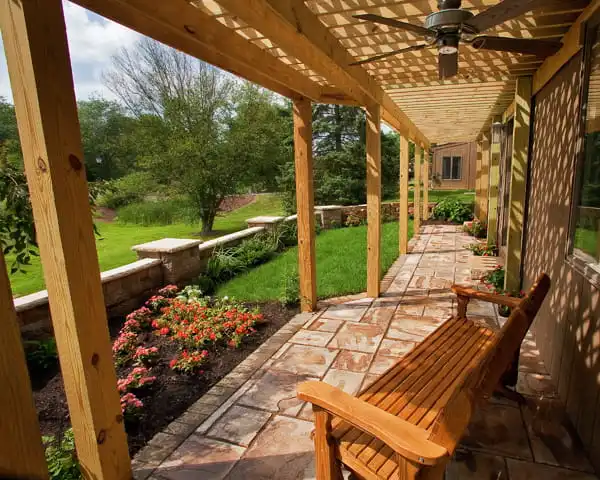 stamped stone patio wood bench under pergola